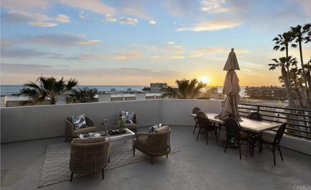 Rooftop deck sofas, dining table and sunset over the palms