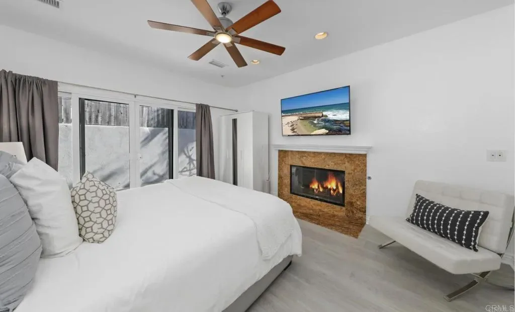 Bedroom with gas fireplace, ceiling fan and slider to the patio