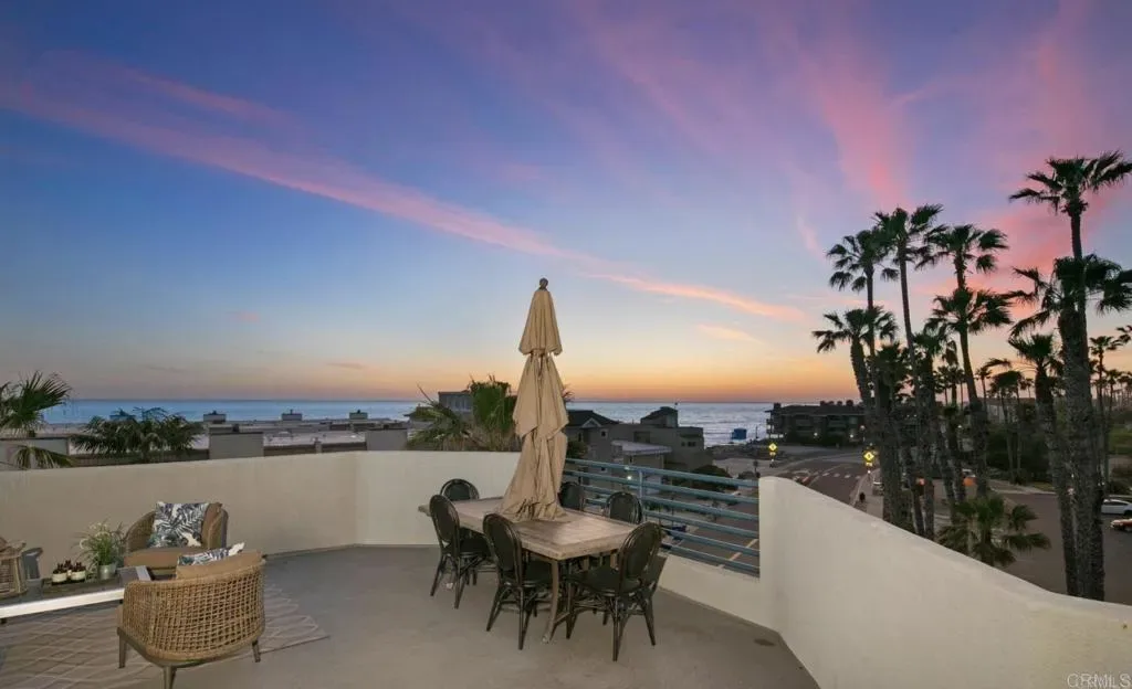 Rooftop deck at twilight with dining table and umbrella