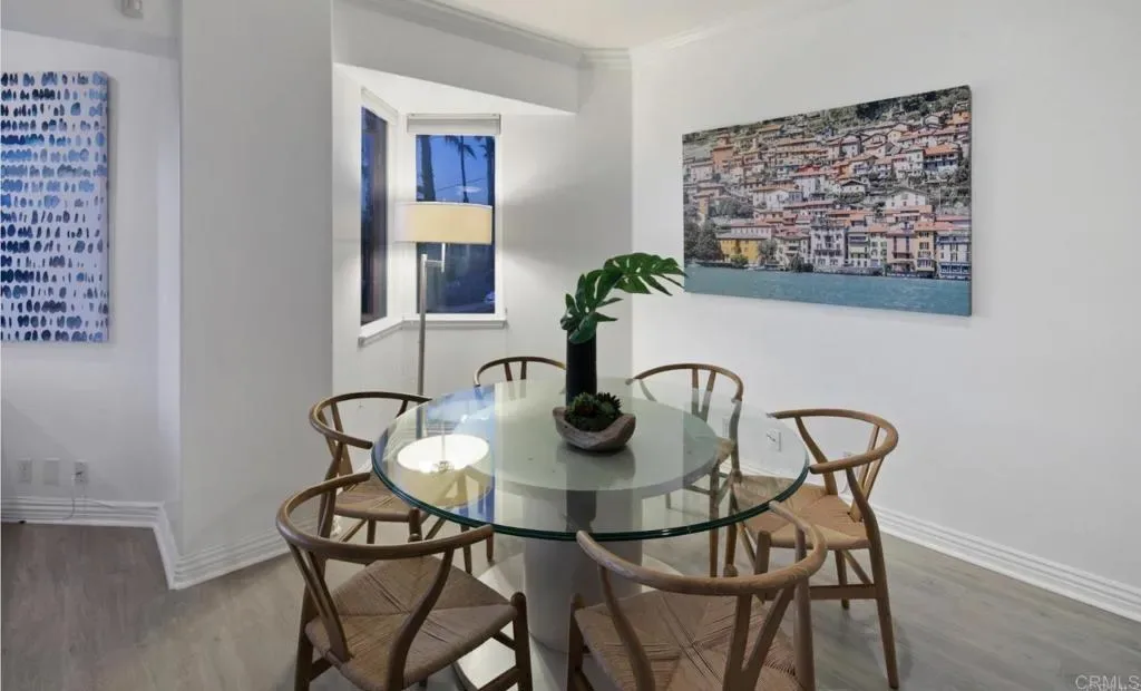 Round glass dining table under coastal artwork