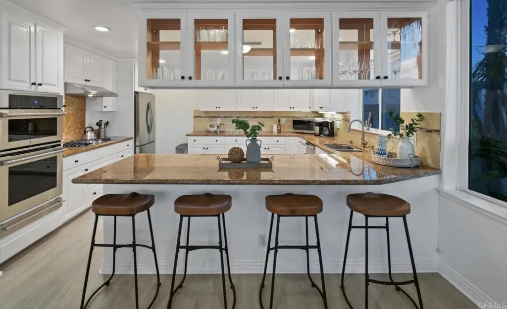 Kitchen island with four stools and glass-front cabinetry